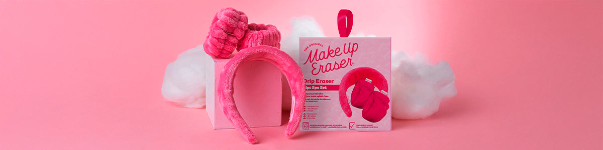 Rosa Haaraccessoires und Makeup Eraser-Verpackungen auf rosa Hintergrund mit flauschigen weißen Wolken.