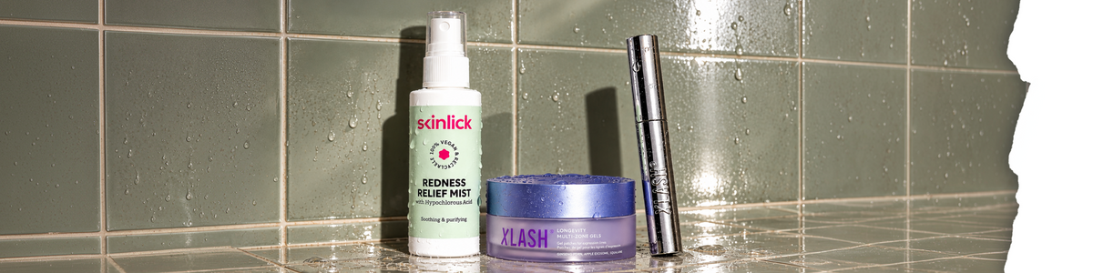 Skinlick Redness Relief Mist, Xlash Longevity Multi-Zone Gels und eine Xlash-Tube, die auf einer gefliesten Oberfläche mit Wassertropfen steht.