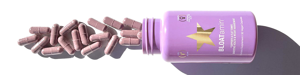 Aus einer lavendelfarbenen „BLOATamin“-Flasche sind violette Nahrungsergänzungskapseln auf einer weißen Oberfläche verschüttet.