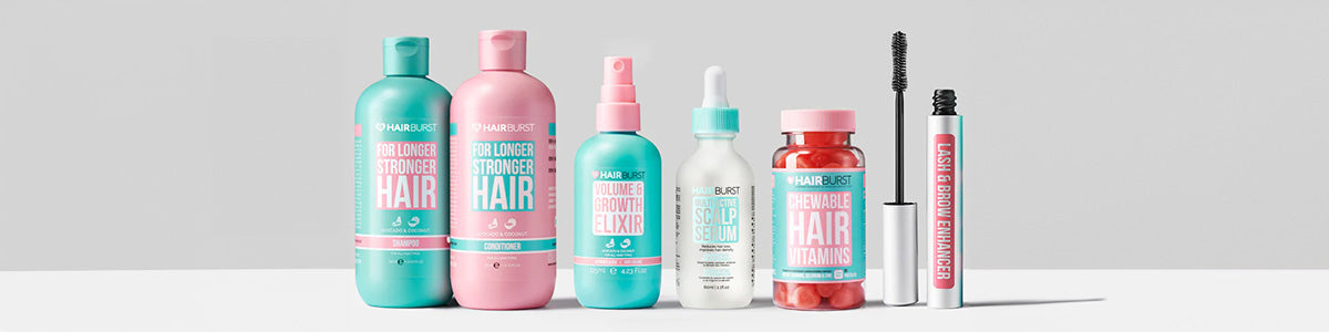 Eine Reihe farbenfroher Hairburst-Haarpflege- und Schönheitsprodukte auf einer weißen Oberfläche vor hellem Hintergrund.