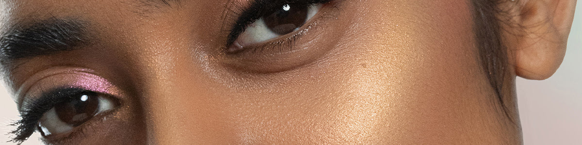 Nahaufnahme der Augen einer Person mit rosa und golden schimmerndem Lidschatten und strahlender, mit hervorgehobener Haut.