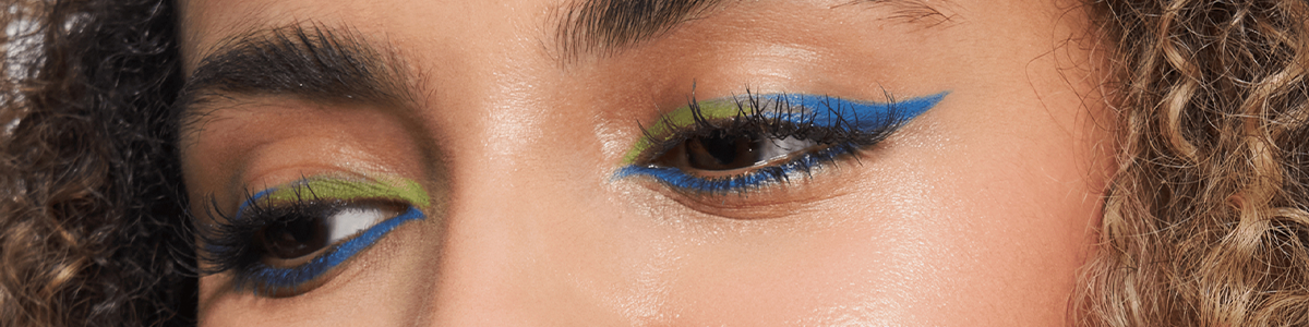 Nahaufnahme von Augen mit grünem Lidschatten und auffälligem blauem Eyeliner in Cat-Eye-Form.