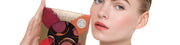 Frau mit natürlichem Make-up hält ein Danessa Myricks Beauty Set mit mehreren Cremetiegeln in der Hand.