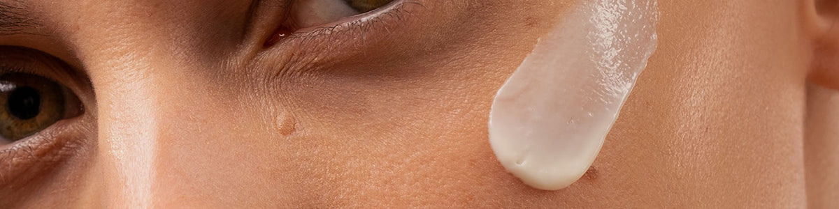 Nahaufnahme einer Person, etwas unterhalb der Augenpartie, mit aufgetragener Creme unter dem Auge.