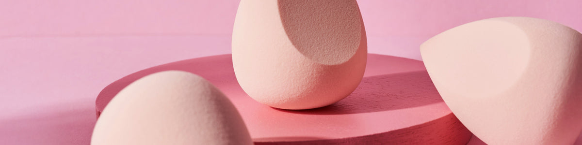 Drei rosa Make-up-Schwämme auf einer rosa runden Plattform mit rosa Hintergrund.