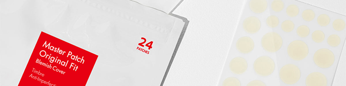 Nahaufnahme einer Packung mit 24 Pflastern gegen Pickel neben einem Blatt mit runden Pickelpflastern.