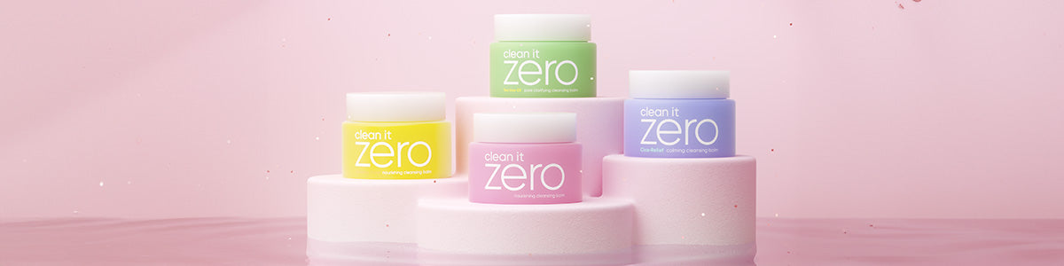 Vier bunte Clean It Zero Abschmink-Balsame von Banila Co auf rosa Podesten, vor pastellfarbenem Hintergrund.