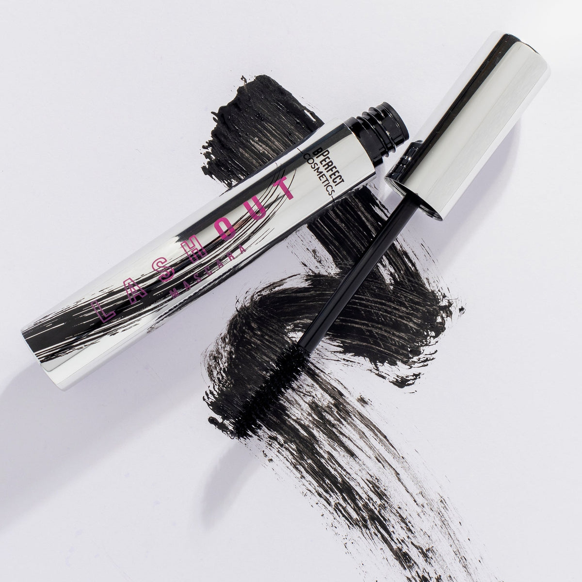 Geöffnete silberne Tube und Bürste der Lash Out Mascara vor schwarzem Swatch auf weißem Hintergrund.