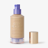 Eine Flasche Skin Realist Tinted Balm in der Farbe 2 Light mit einem violetten Pumpspender und einem goldenen Deckel daneben.