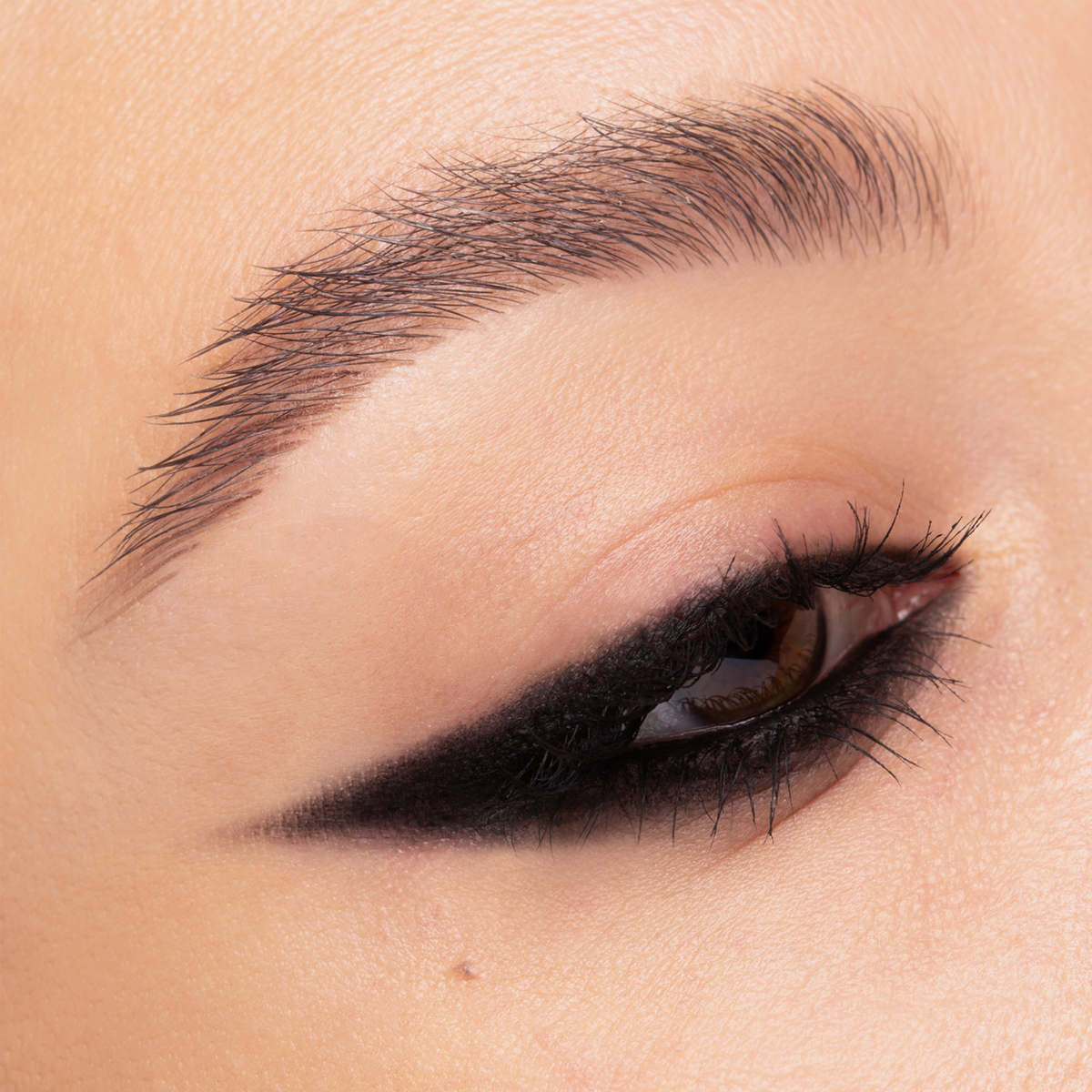 Nahaufnahme eines Auges mit kantigem, schwarzen Winged-Liner-Look. Der Liner verläuft spitz nach außen, die Wimpern sind definiert.