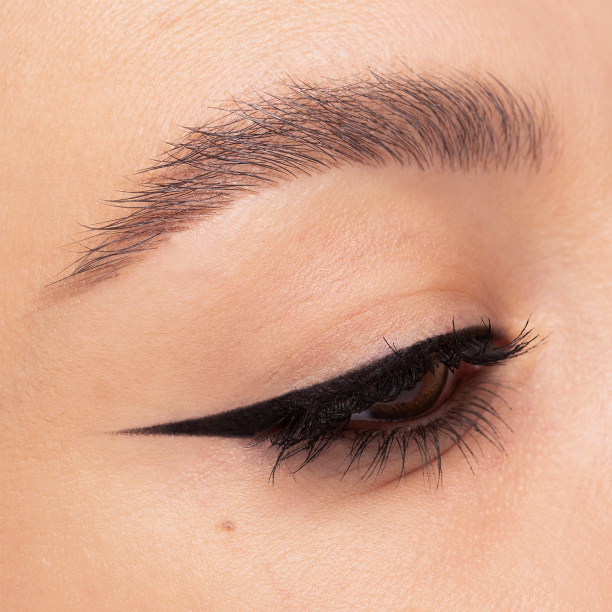 Nahaufnahme eines Auges mit klassischem schwarzen Eyeliner. Der präzise Wing zieht sich scharf nach außen, Wimpern sind betont.