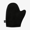 Der Luxe Tanning Mitt, ein schwarzer Fäustling mit kleinem Etikett an der Seite, vor weißem Hintergrund