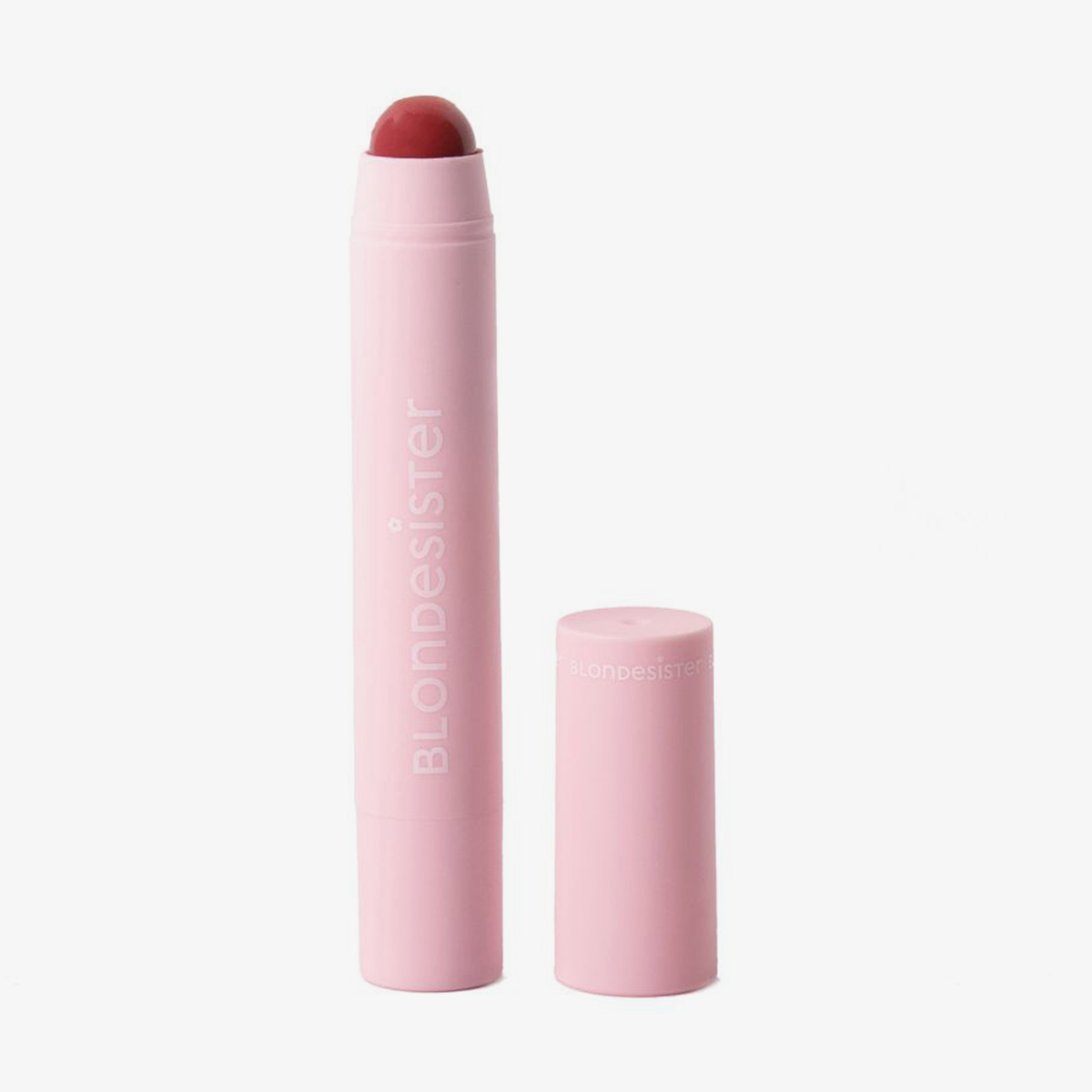 Ein „BLONDESISTER 2 IN 1 – IT’S UP TO YOU LIP OR CHEEK“-Stift in Rosa mit seiner Kappe daneben auf weißem Hintergrund.