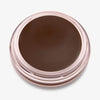 Ein runder offener Behälter mit Cronzer Cream Bronzer Oak mit dunkelbraunem Inhalt auf weißem Hintergrund.