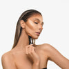 Eine Frau mit nach hinten gegelten Haaren trägt den Shapestick Bronze & Define auf ihr Gesicht auf und konturiert Wangen, Nase und Kinn.