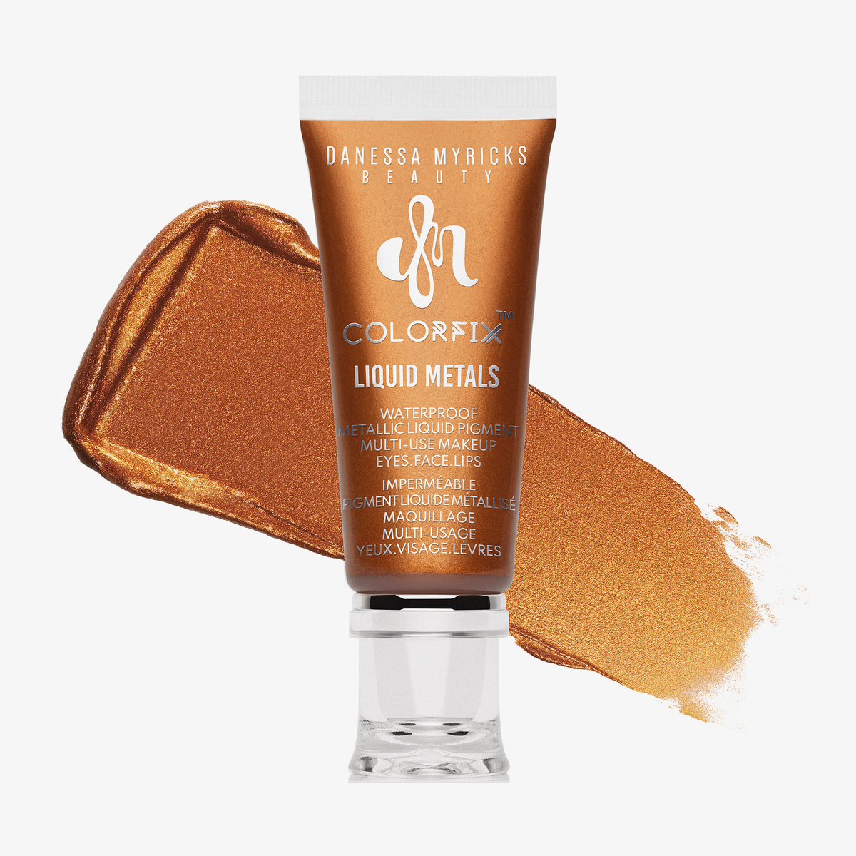 Tube mit metallisch-bronzenem Flüssigpigment von Danessa Myricks Beauty, Produktname „Colorfix Liquid Metals – Spark“, mit Farbswatch im Hintergrund.
