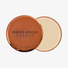 Rundes Mini Yummy Skin Blurring Balm Powder Universal mit beigem Creme-Puder und einem bronzefarbenem Deckel auf weißem Hintergrund.