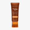 Bronzefarbene Tube der Yummy Skin Serum Tint 5 mit Sichtfenster zum warm-beigen Produktinhalt.