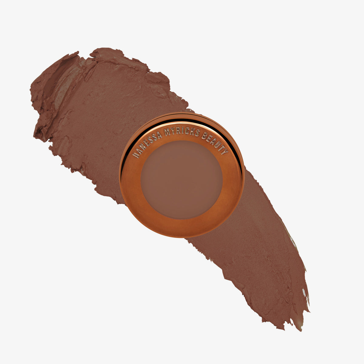 Yummy Skin Blurring Balm Powder Flushed Creme Brulee in rundem bronzenem Behälter auf dunkelbraunem Farbmuster abgebildet.