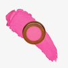 Yummy Skin Blurring Balm Powder Flushed It Girl in rundem bronzenem Behälter auf pinkem Farbmuster abgebildet.