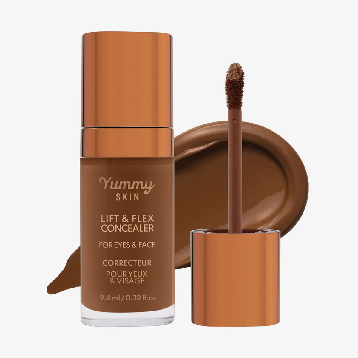 Eine transparente Flasche Yummy Skin Lift & Flex Concealer 15 neben einem bronzenen Applikator vor dunkelbraunem Farbmuster.