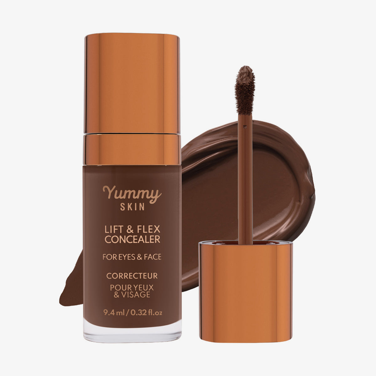 Eine transparente Flasche Yummy Skin Lift & Flex Concealer 17 neben einem bronzenen Applikator vor tiefbraunem Farbmuster.