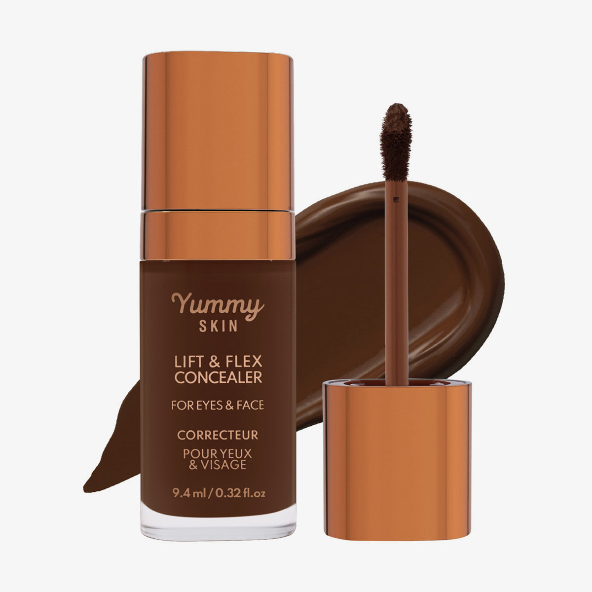 Eine transparente Flasche Yummy Skin Lift & Flex Concealer 18 neben einem bronzenen Applikator vor tiefbraunem Farbmuster.