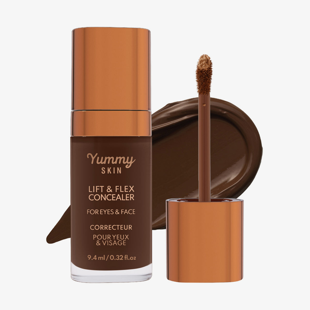 Eine transparente Flasche Yummy Skin Lift & Flex Concealer 20 neben einem bronzenen Applikator vor tiefbraunem Farbmuster.