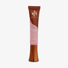 Eine rosa und bronzefarbene Tube Yummy Skin Glow Serum Fresh Pressed vor weißem Hintergrund.
