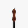 Nahaufnahme des Dominique Cosmetics Lash Lift Tubing Mascara-Stabs mit brauner Wimperntusche vor einem schlichten weißen Hintergrund.