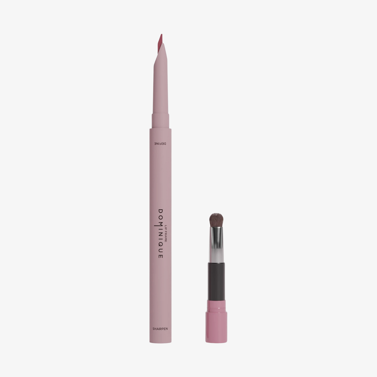 Der Dominique Cosmetics Lip Frame Pencil in der Farbe Cool Girl Pink und der zugehörige Pinselapplikator vor weißen Hintergrund.