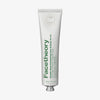 Weiße Tube Double Glow Exfoliating Face & Body Scrub mit grünem Text auf weißem Hintergrund.