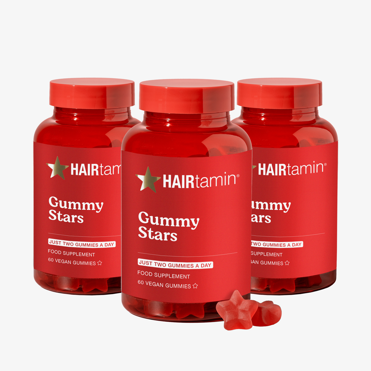 Drei Flaschen HAIRtamin Gummy Stars™ im 3-Monats-Paket mit roten, sternförmigen Gummibonbons im Vordergrund.