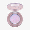 Offene transparente Kompaktdose des Pressed Opal Multichrome Eyeshadow Birdsong mit lila-blau schimmerndem gepressten Lidschatten auf weißem Hintergrund.