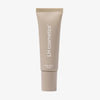 Beige Tube aus dem LH Cosmetics Makeup meets Skincare Holiday Kit, aufrecht stehend auf weißem Hintergrund.