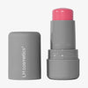 Neben der Tube steht eine graue Tube LH Cosmetics Artistick Blush mit einem leuchtend rosa Stift ohne Deckel.