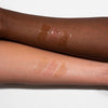 Zwei Arme mit unterschiedlichen Hauttönen zeigen drei glänzende und glitzernde Farbmuster des Glazed Lipgloss von LH Cosmetics.