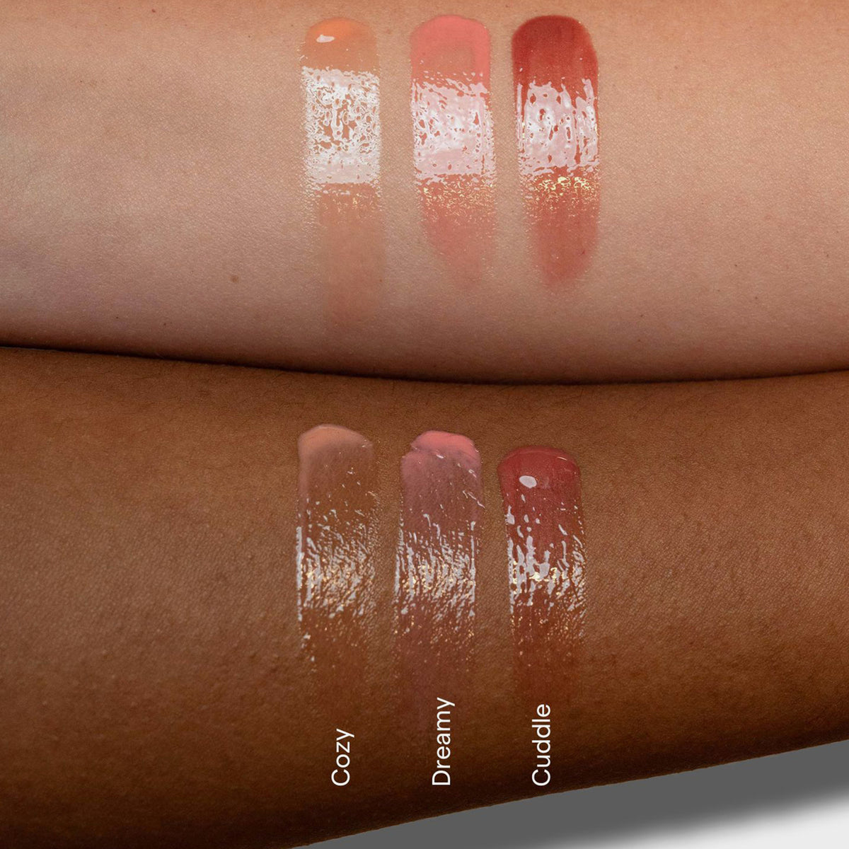 Farbmuster der glänzenden Lippenfarben des Plush von LH Cosmetics in Beige (Cozy), Rosa (Dreamy) und Mauve (Cuddle), gezeigt auf hellen und dunklen Hauttönen.