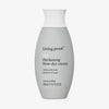 Eine graue bauchige Flasche Living Proof Full Thickening Blow-Dry Cream mit weißem Deckel vor weißem Hintergrund.