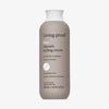 Beige Flasche Living Proof No Frizz Smooth Styling Cream mit weißem Deckel vor weißem Hintergrund.
