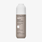 Beige Flasche Living Proof No Frizz Smooth Styling Spray mit weißem Deckel vor weißem Hintergrund.