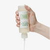 Eine Hand hält eine umgedrehte Flasche mit Mario Badescu Glycolic Foaming Cleanser, während das Produkt ausgegeben wird.