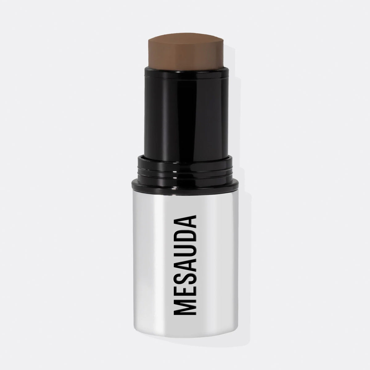 Ein silber-schwarzer Make-up-Stick mit dem leicht herausgedrehten The Mood Contrast 103 Dark von Mesauda vor weißem Hintergrund.