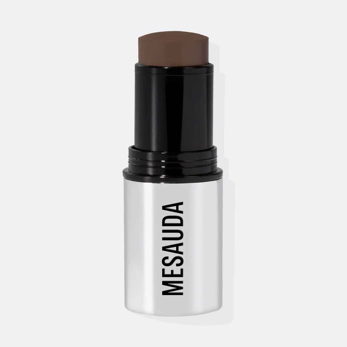 Ein silber-schwarzer Make-up-Stick mit dem leicht herausgedrehten The Mood Contrast 104 Deep von Mesauda vor weißem Hintergrund.