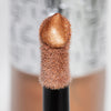 Nahaufnahme des Highlighter-Applikators; darauf ein Tropfen Flush of Light Sunset Bronze mit strukturierter silber Kappe im Hintergrund.