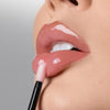 Eine Nahaufnahme zeigt eine Person, die das LIPOILOGY™ glossy pink lip oil von Mesauda Beauty mit dem Applikator auf ihre Lippen aufträgt.