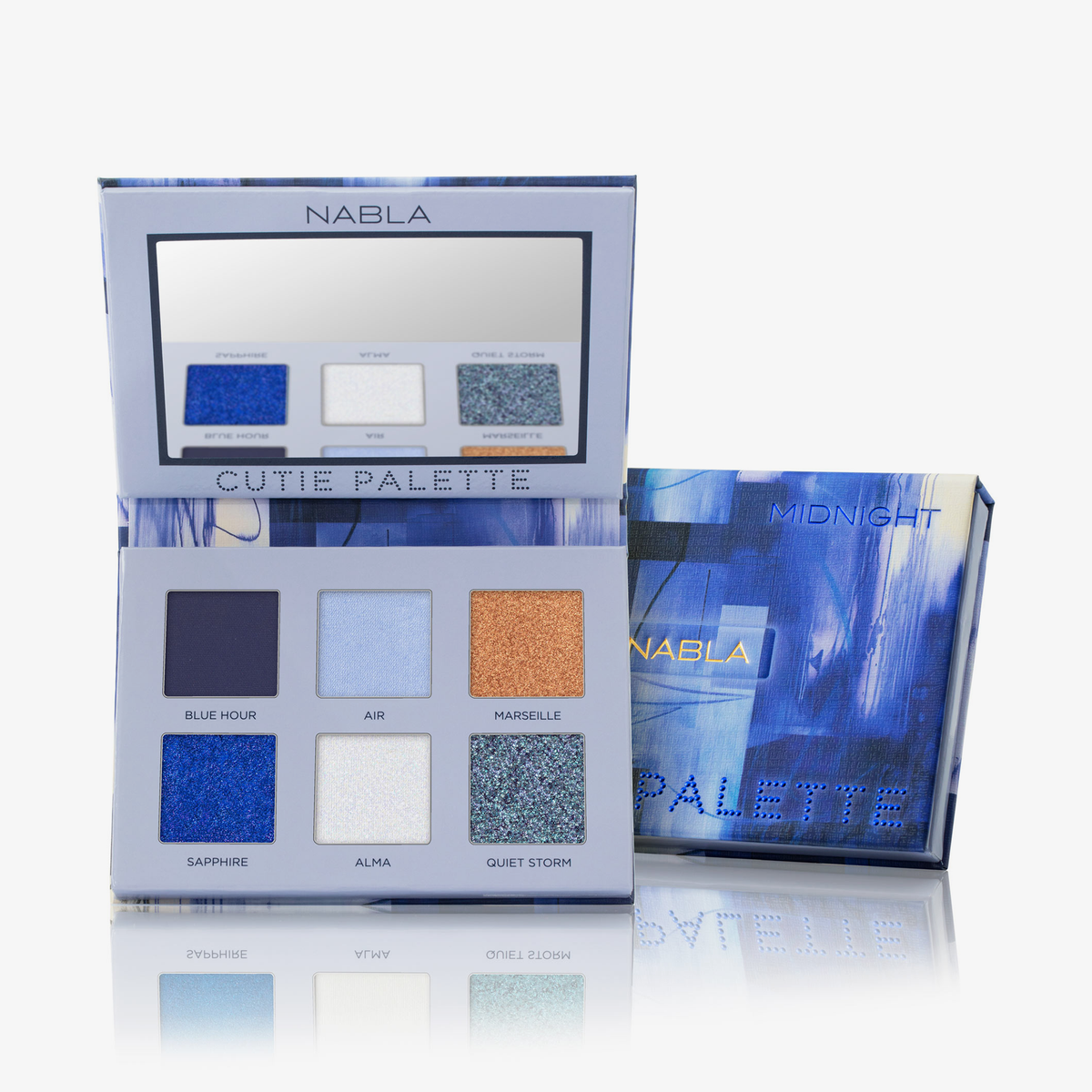 Die Cutie Palette - Midnight - von Nabla mit sechs Lidschattentönen und einem Spiegel wird geöffnet neben ihrer blauen Verpackungsbox präsentiert.