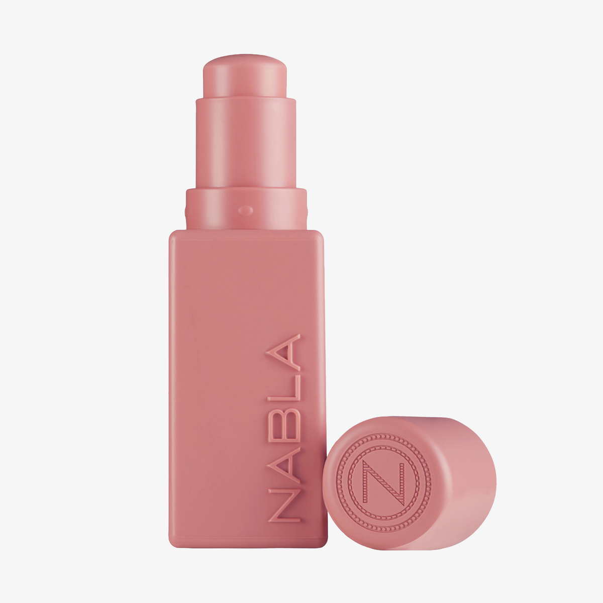 Ein rosa, rechteckiger „Art Of Skin Blush Stick“ in Bloomy von NABLA Cosmetics mit der dazugehörigen Kappe daneben auf weißem Hintergrund.