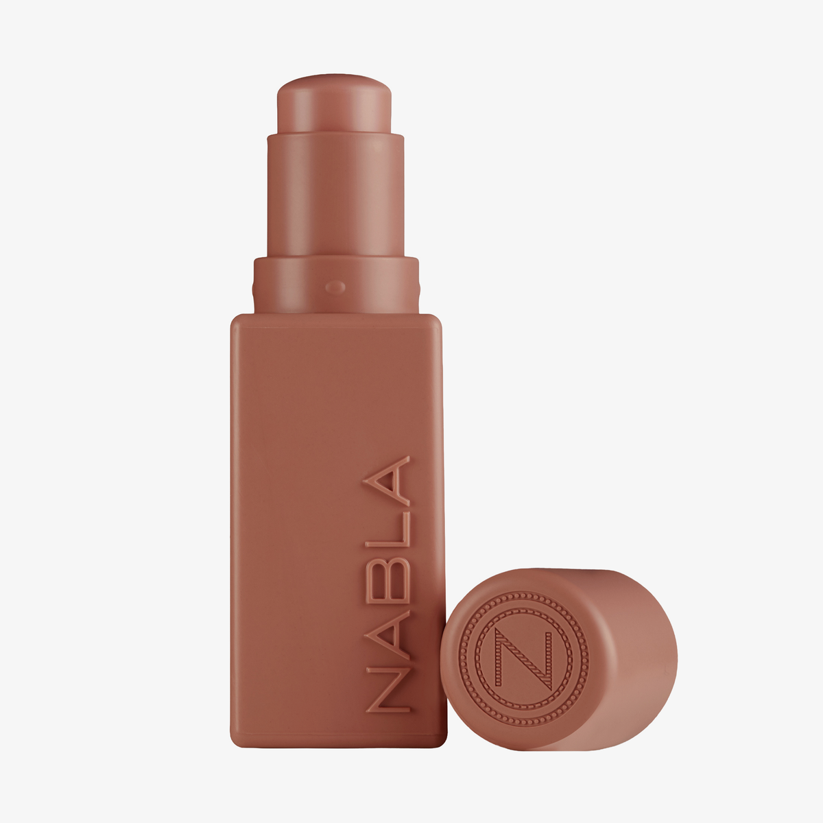 Ein nudefarbener „Art Of Skin Blush Stick“ Toasty von NABLA Cosmetics mit einer dazu passenden Kappe daneben.