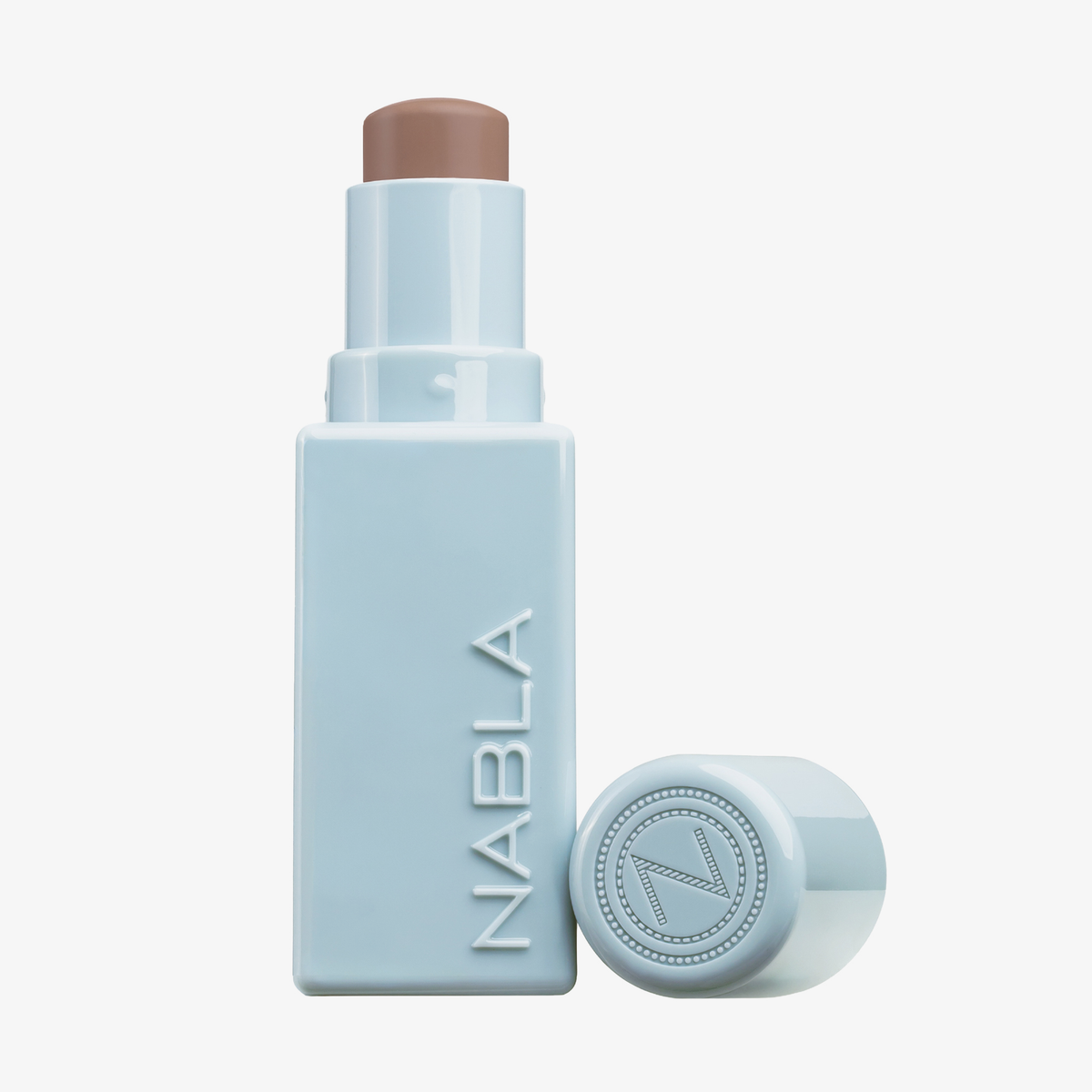 Ein hellblauer NABLA Cosmetics Contour Stick mit abgenommener Kappe, die die beige Creme im Inneren zeigt.